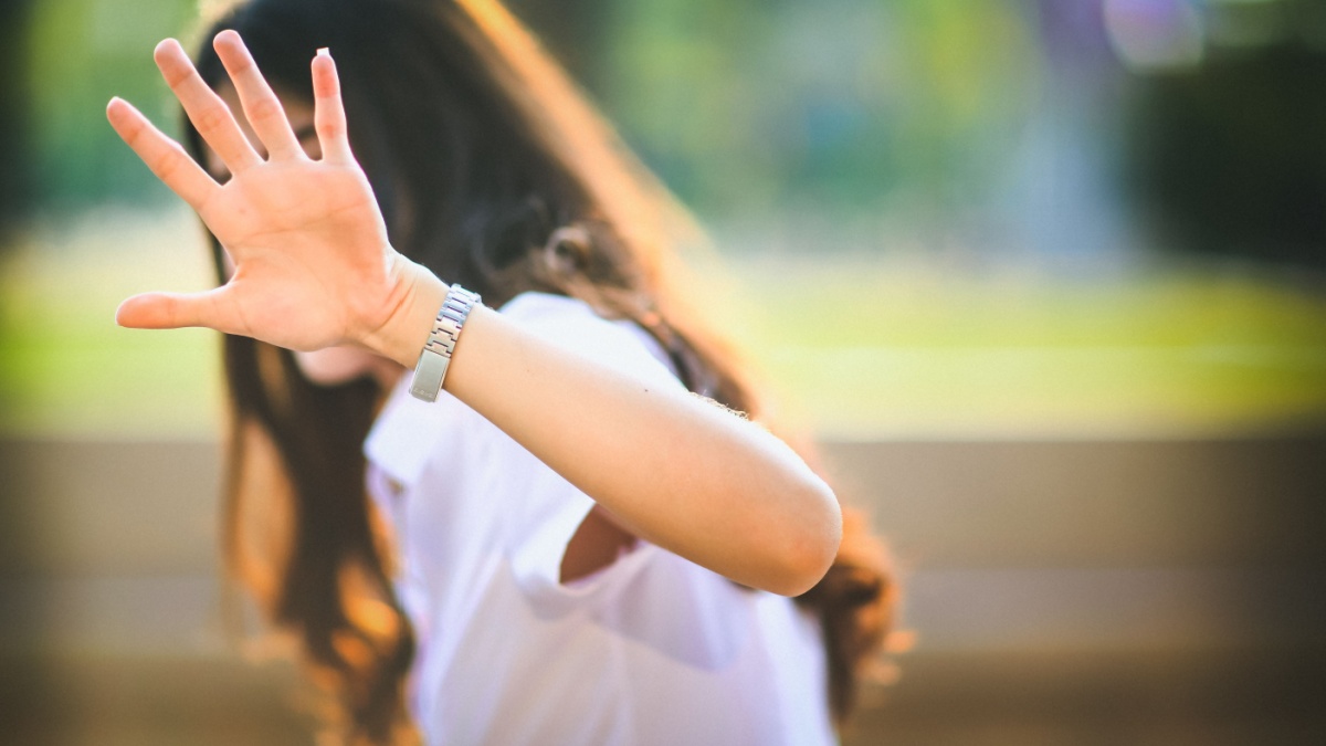 Girl show hand up, symbol of stop. invisible face, a young girl with hand out. body language to say