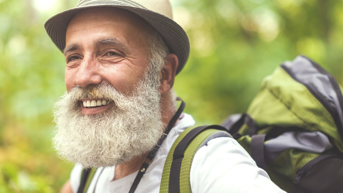 Cheerful old man admiring the nature during hiking.