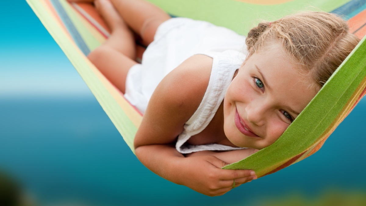 Summer vacation - lovely girl in colorful hammock.