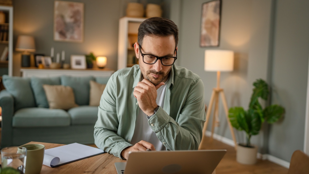 one man adult caucasian male with beard work on his laptop computer at home solve problem freelance entrepreneur or remote work concept.