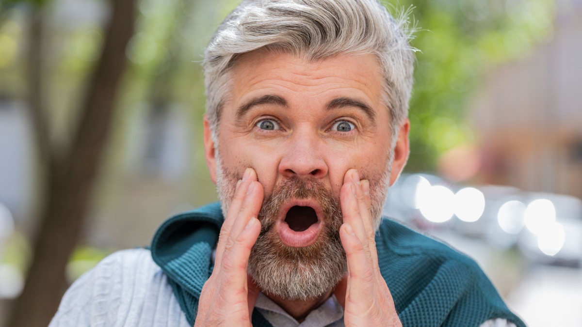 Oh my god, wow. Caucasian mature man looking surprised at camera with big open eyes, shocked by sudden victory, game winning, lottery goal.