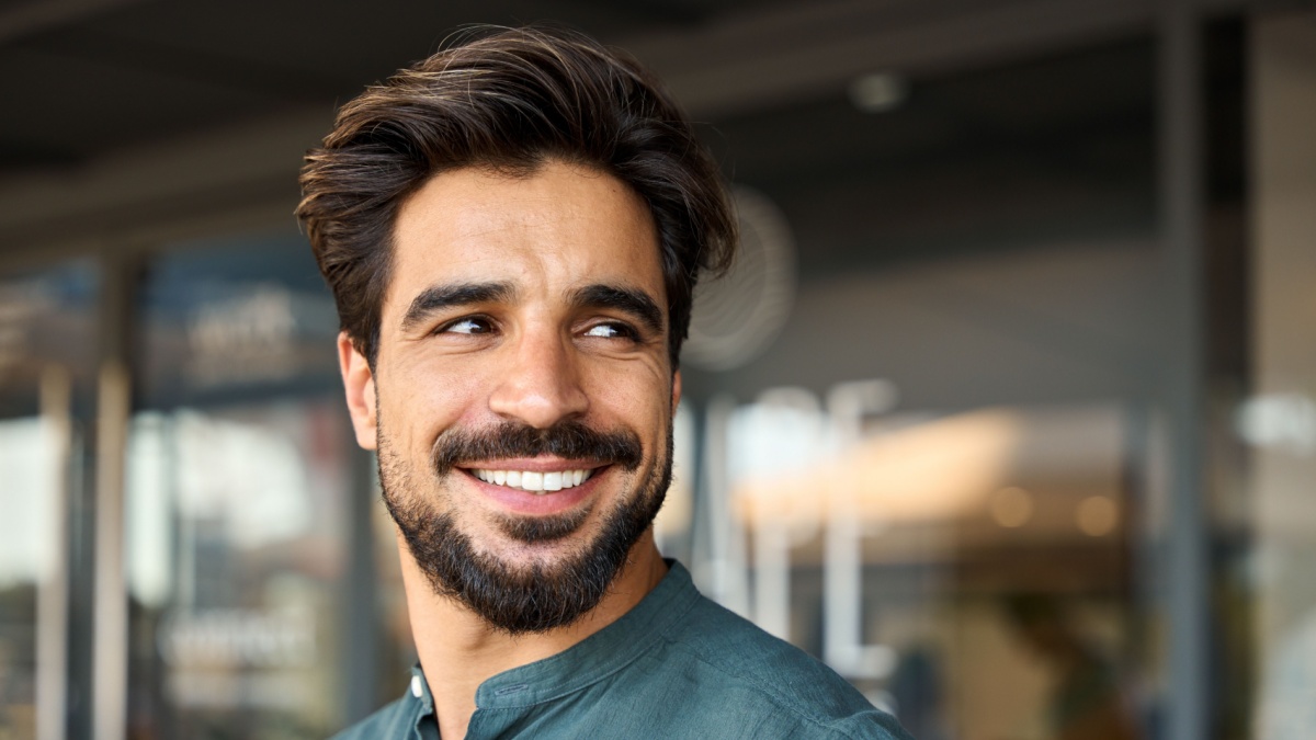 Smiling young business man standing looking away in office.