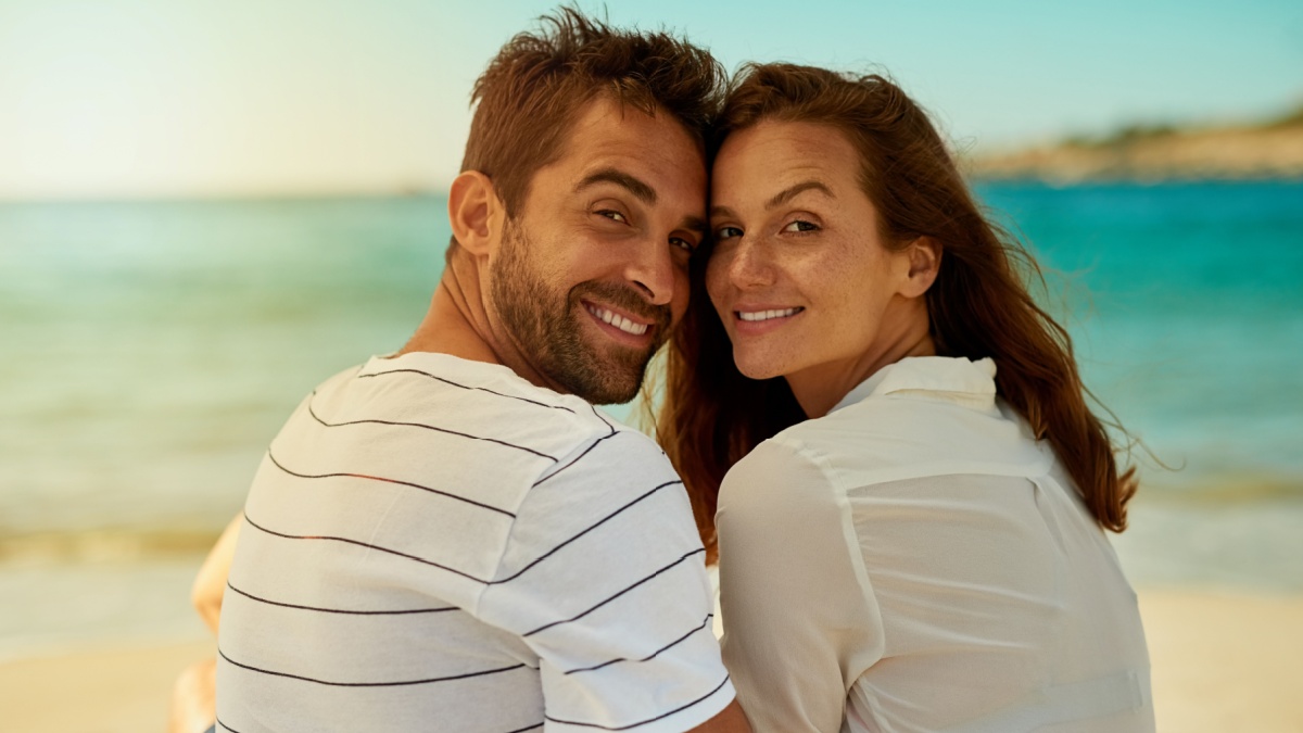 Back, portrait and smile with couple on beach together for anniversary, holiday date or romance in summer.